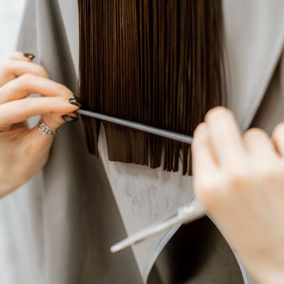 Hairdresser's hands cutting hair. Long brunette hair, grooming and haircut at the hairdresser. Beauty salon for women